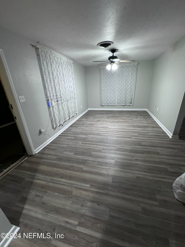 spare room featuring a textured ceiling, ceiling fan, and dark wood-type flooring