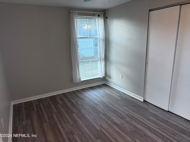 unfurnished bedroom featuring ceiling fan, dark wood-type flooring, and a closet