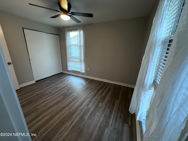 unfurnished bedroom featuring ceiling fan, dark wood-type flooring, and a closet