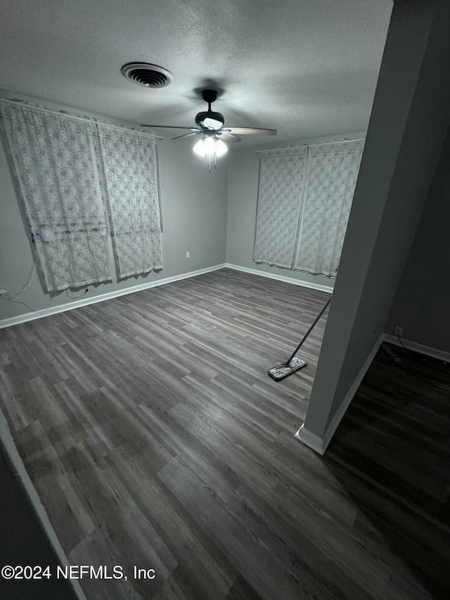 empty room featuring a textured ceiling, dark hardwood / wood-style floors, and ceiling fan