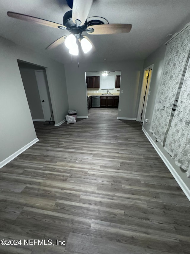 unfurnished living room featuring a textured ceiling, ceiling fan, dark wood-type flooring, and sink