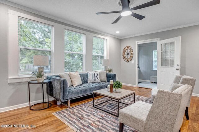 living room featuring light wood-type flooring, crown molding, and ceiling fan