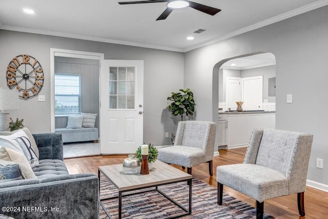 living room with crown molding, light hardwood / wood-style floors, and ceiling fan