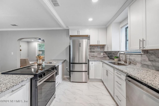 kitchen featuring appliances with stainless steel finishes, light stone countertops, sink, and white cabinets