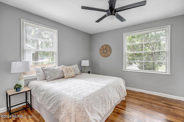 bedroom featuring multiple windows, hardwood / wood-style floors, and ceiling fan