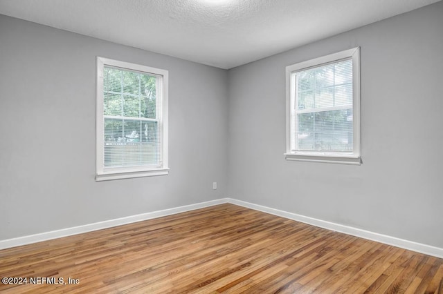 empty room with a textured ceiling and light hardwood / wood-style flooring