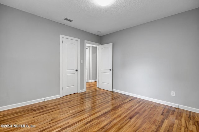 empty room with a textured ceiling and light hardwood / wood-style floors