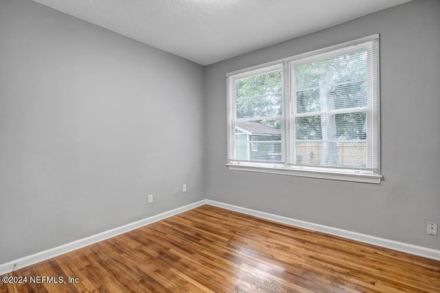 empty room with hardwood / wood-style floors and a textured ceiling