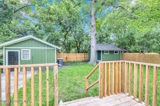 wooden terrace featuring a storage unit and a yard