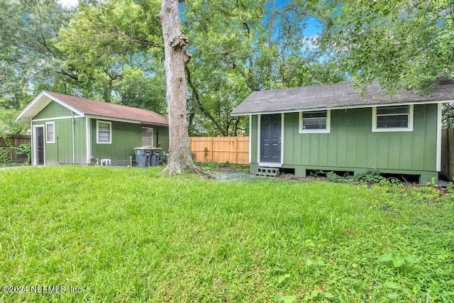 rear view of property featuring an outdoor structure and a lawn