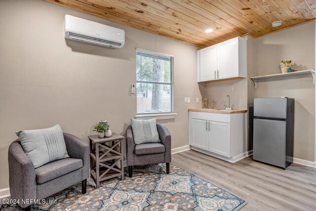 living area with light hardwood / wood-style floors, sink, wood ceiling, and an AC wall unit