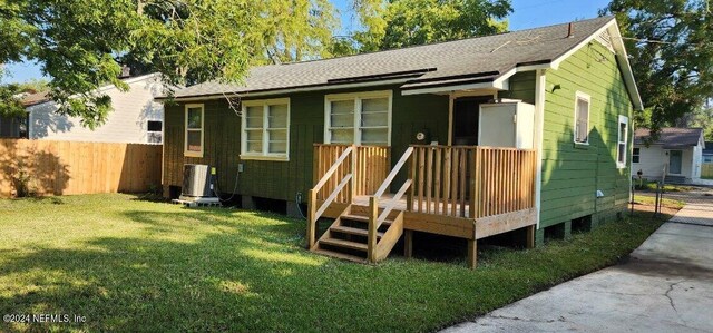 view of front of house with a front lawn, a wooden deck, and central air condition unit