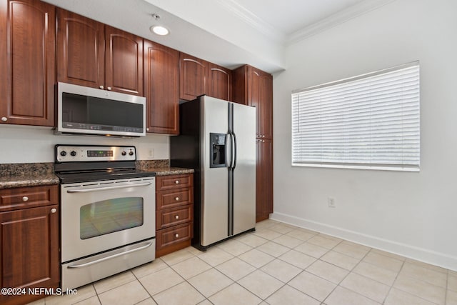 kitchen featuring dark stone countertops, light tile patterned floors, appliances with stainless steel finishes, and ornamental molding