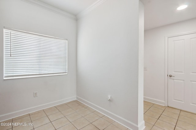 empty room featuring light tile patterned flooring, crown molding, and plenty of natural light