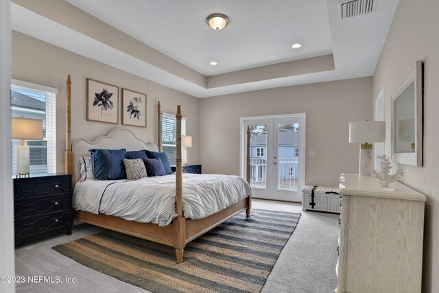 carpeted bedroom with a raised ceiling, access to exterior, and french doors