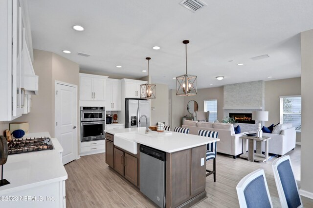 kitchen featuring stainless steel appliances, light countertops, visible vents, a sink, and a kitchen breakfast bar