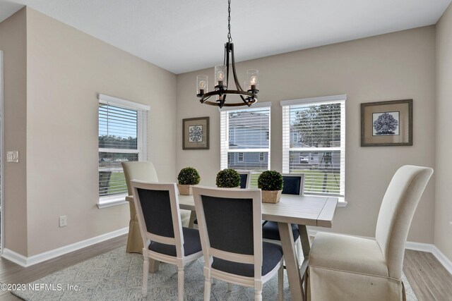 dining area with a chandelier, wood finished floors, and baseboards