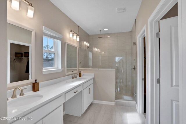 bathroom featuring marble finish floor, a sink, a shower stall, and double vanity