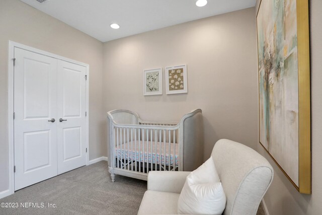 carpeted bedroom featuring a crib and a closet