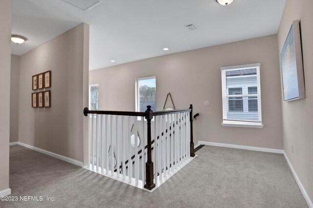 corridor featuring carpet, baseboards, visible vents, and an upstairs landing