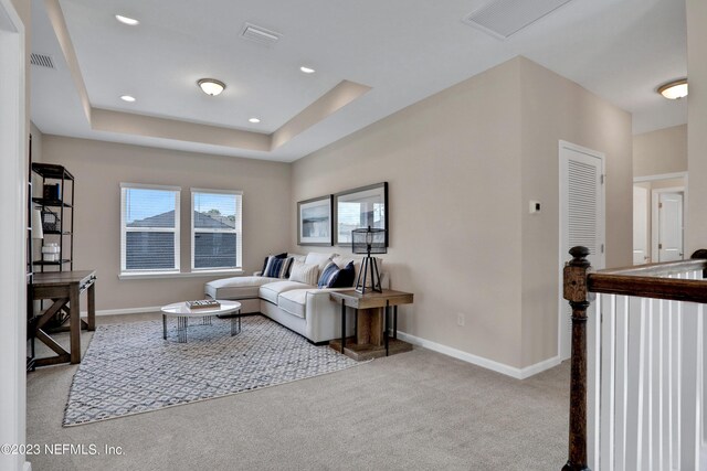 living room with light colored carpet and a tray ceiling