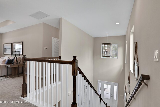 stairway featuring carpet floors and a chandelier