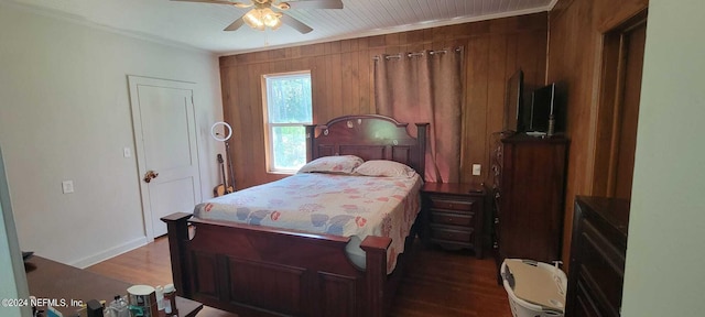 bedroom featuring ceiling fan, crown molding, wooden walls, and dark hardwood / wood-style floors