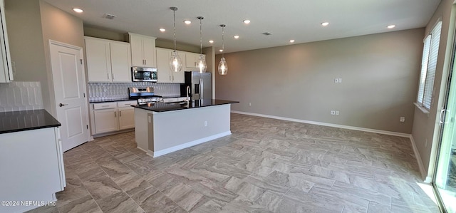 kitchen featuring stainless steel appliances, a kitchen island with sink, white cabinets, and decorative light fixtures