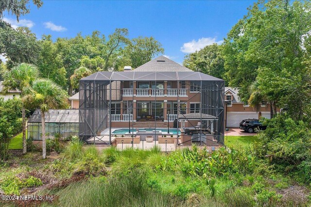 back of property featuring glass enclosure, a swimming pool with hot tub, and a patio area