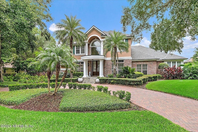 view of front of property with a front lawn, decorative driveway, and brick siding