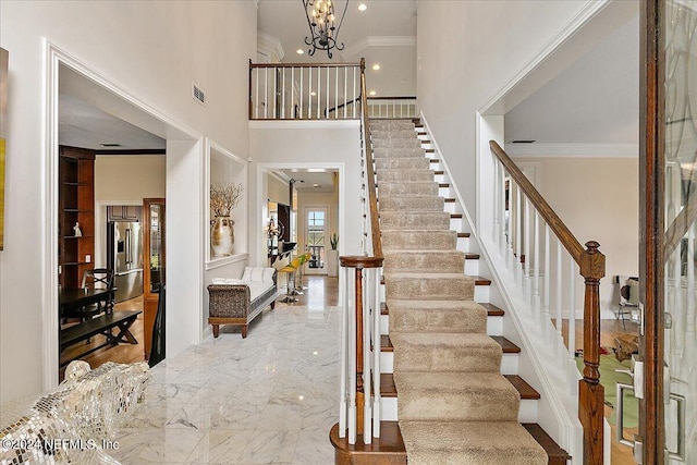 entryway with crown molding, visible vents, marble finish floor, stairway, and an inviting chandelier