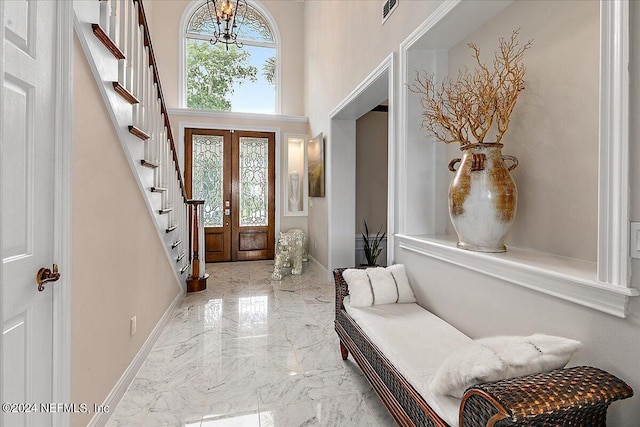 foyer featuring marble finish floor, french doors, a towering ceiling, stairway, and baseboards