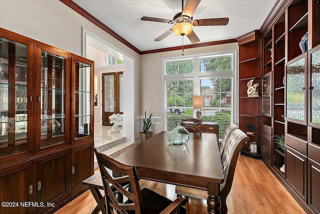 dining space featuring light wood finished floors, ceiling fan, ornamental molding, and a textured ceiling