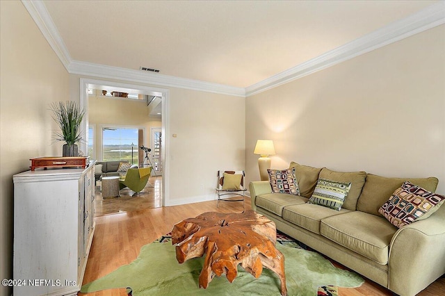 living area featuring visible vents, crown molding, light wood-style flooring, and baseboards