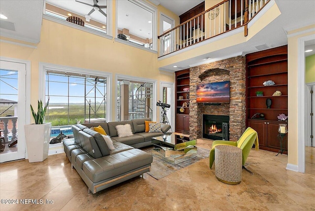 living room featuring built in features, a fireplace, a towering ceiling, and ornamental molding