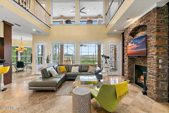 living room featuring visible vents, a stone fireplace, a towering ceiling, and an inviting chandelier