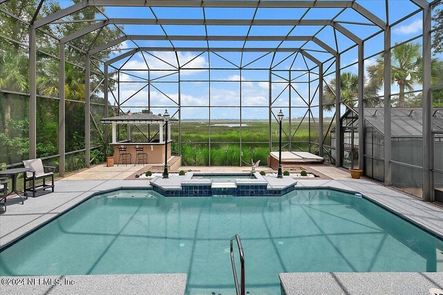 view of swimming pool featuring glass enclosure, an in ground hot tub, and a patio area