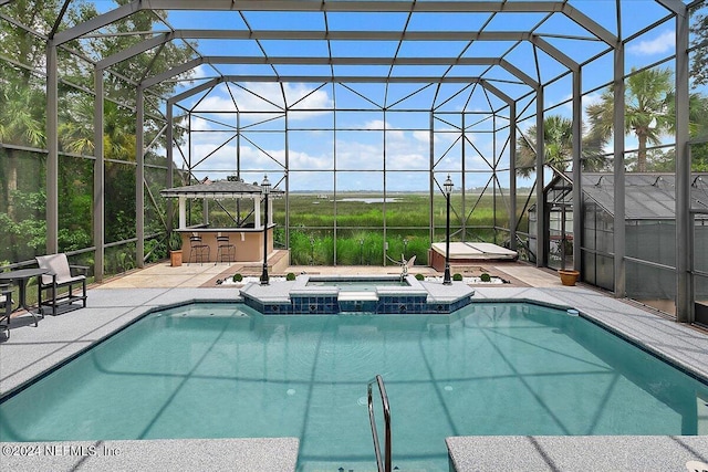 view of swimming pool featuring outdoor dry bar, glass enclosure, a patio area, and a pool with connected hot tub