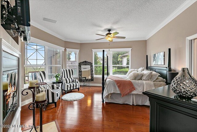 bedroom featuring a textured ceiling, baseboards, wood finished floors, and crown molding