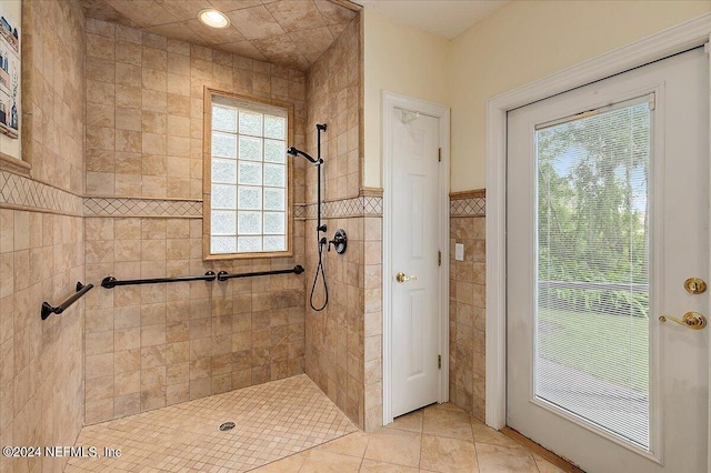 full bath with wainscoting, tile walls, tiled shower, and tile patterned floors