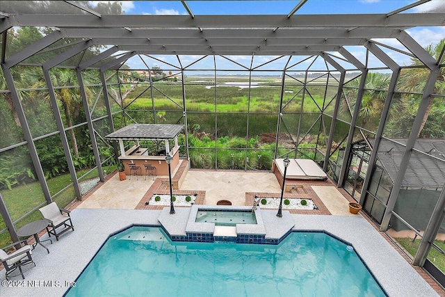 pool featuring outdoor dry bar, a patio, a lanai, and an in ground hot tub