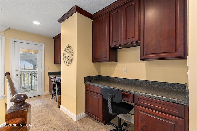 office space with baseboards, light colored carpet, a textured ceiling, built in desk, and recessed lighting