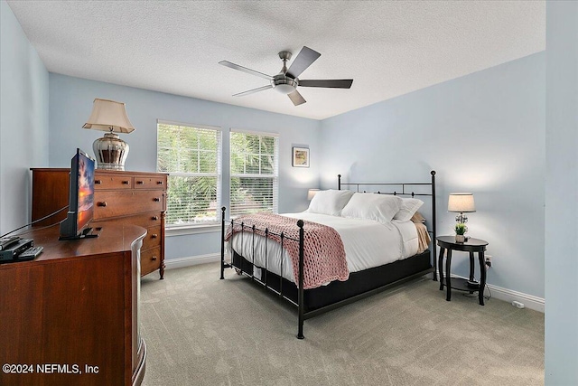 bedroom featuring light carpet, a textured ceiling, a ceiling fan, and baseboards