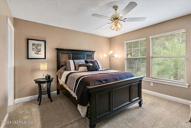 bedroom with light carpet, a ceiling fan, baseboards, and a textured ceiling