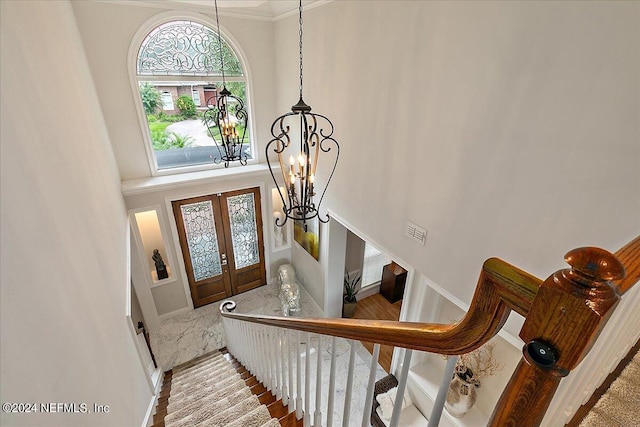 entryway featuring visible vents, a towering ceiling, stairs, french doors, and an inviting chandelier