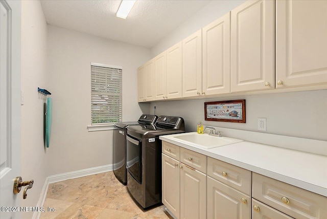 laundry area featuring a textured ceiling, a sink, baseboards, independent washer and dryer, and cabinet space