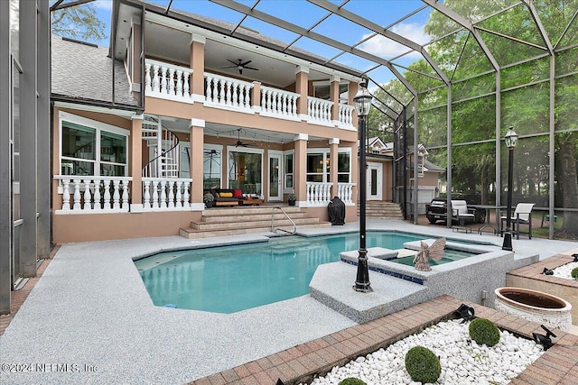 outdoor pool featuring glass enclosure, a fire pit, a ceiling fan, stairway, and a patio area