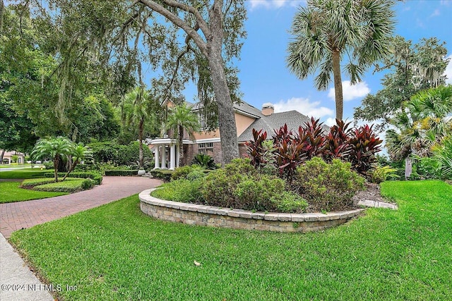 view of property exterior with a chimney, decorative driveway, and a yard