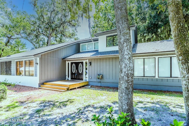 view of front facade featuring a shingled roof, a chimney, and board and batten siding