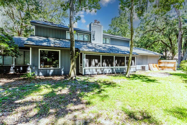 rear view of house with a yard, central AC unit, and a sunroom